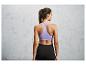 Une femme porte un soutien-gorge de sport violet et un legging noir.