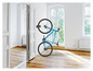 Un vélo bleu accroché au mur dans une pièce vide.