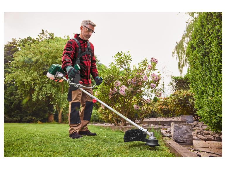 Un homme utilise une débroussailleuse pour couper les herbes.