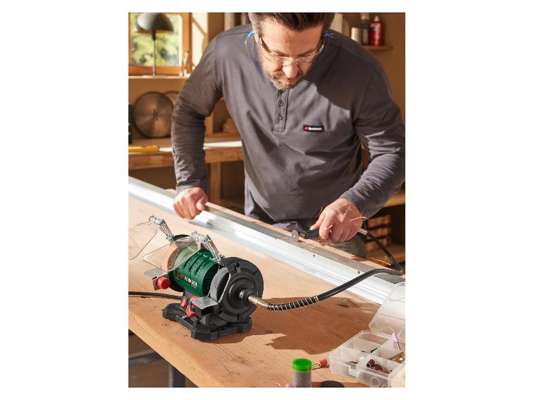 Un homme utilise une meuleuse Parkside pour aiguiser des outils dans son atelier de menuiserie.