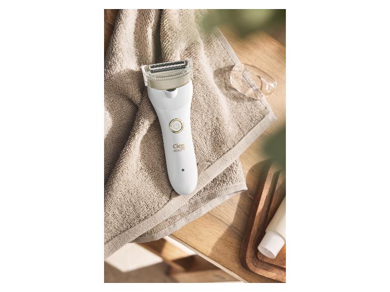 Rasoir électrique blanc pour femme sur une serviette beige, avec le texte « BEAUTY ».