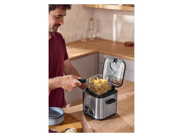 Un homme sort le panier de frites de la mini-friteuse SILVERCREST®.