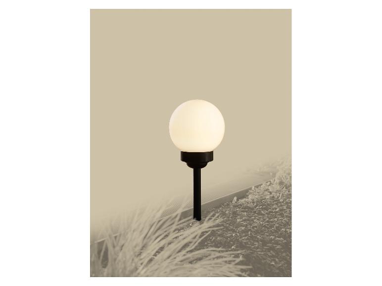 Lumière de jardin sphérique extérieure sur un poteau noir, entourée de plantes et de paillis.