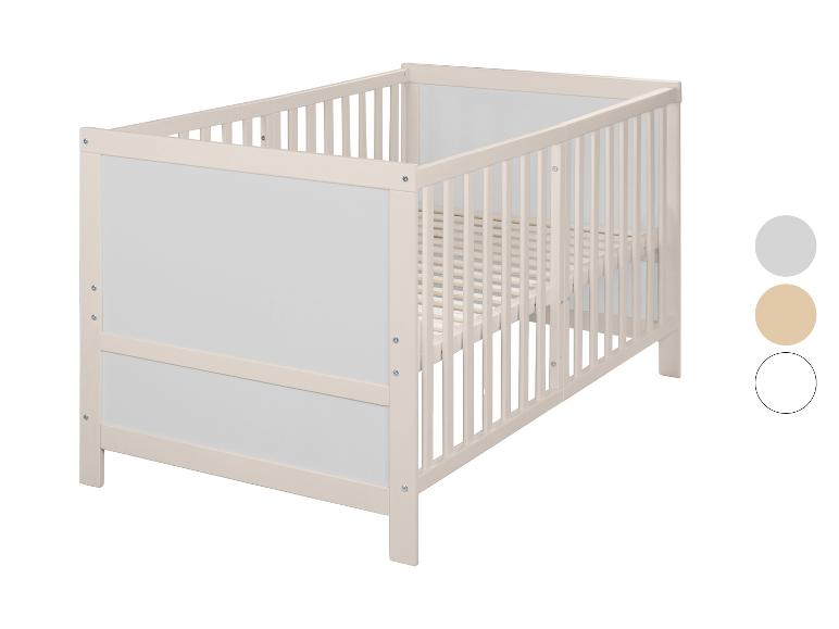 Lit bébé en bois clair avec panneaux blancs et barreaux latéraux.