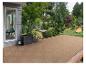 Terrasse extérieure avec dalles en bois, jardin verdoyant et petit étang.