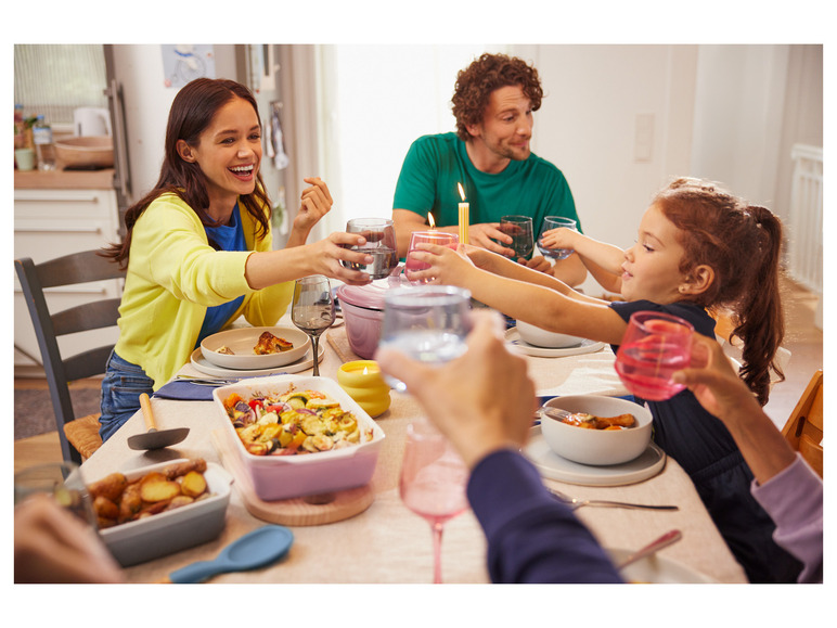 Une famille savoure un repas avec des légumes rôtis, des pommes de terre et des verres d'eau.
