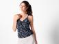 Une femme portant un haut noir à imprimé floral et un pantalon blanc.