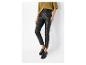 Femme en haut jaune moutarde, pantalon en similicuir noir et mocassins noirs.