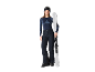 Femme en tenue de ski, incluant pantalon, haut et lunettes, tenant des skis.