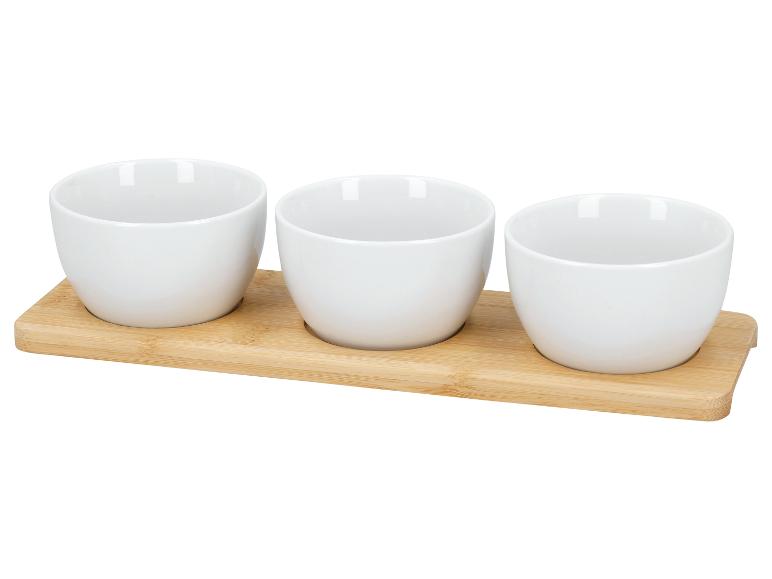 Trois bols en céramique blancs sur un plateau en bambou.