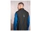 Un homme porte une veste coupe-vent noire à manches longues et un t-shirt bleu à manches longues.