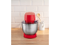 Robot de cuisine rouge avec bol en acier inoxydable sur un comptoir en bois.