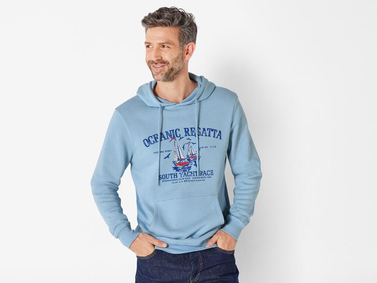 Un homme porte un sweat-shirt bleu avec un motif de voiliers.