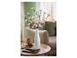 Branches lumineuses LED avec fleurs blanches dans un vase, sur une table en bois avec carnet et lunettes.