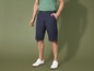 Un homme porte un short cargo bleu et des baskets blanches.