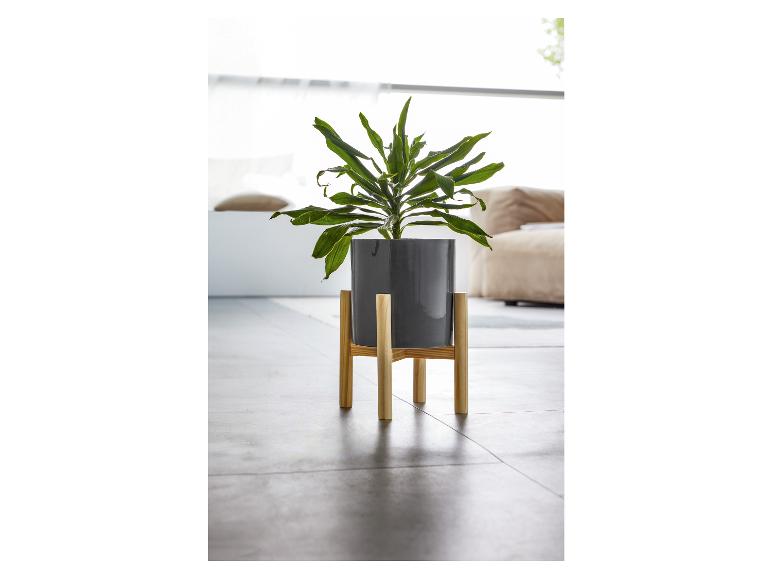 Un pot de fleurs gris sur un support en bois pour plantes.