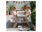 Deux enfants jouent avec une table de pique-nique en bois avec un bac à eau sur une terrasse.