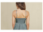 Une femme porte une robe verte en satin avec des bretelles fines.