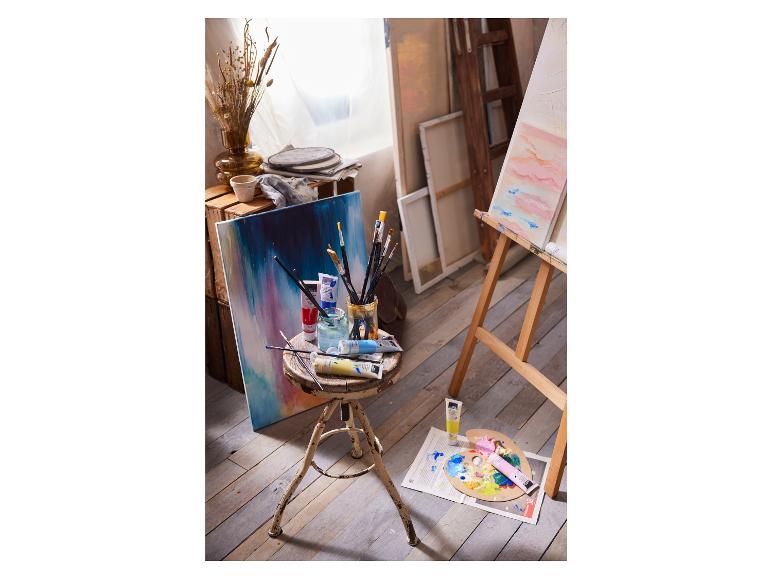 Un atelier d'artiste avec un chevalet, de la peinture, des pinceaux et un tableau.