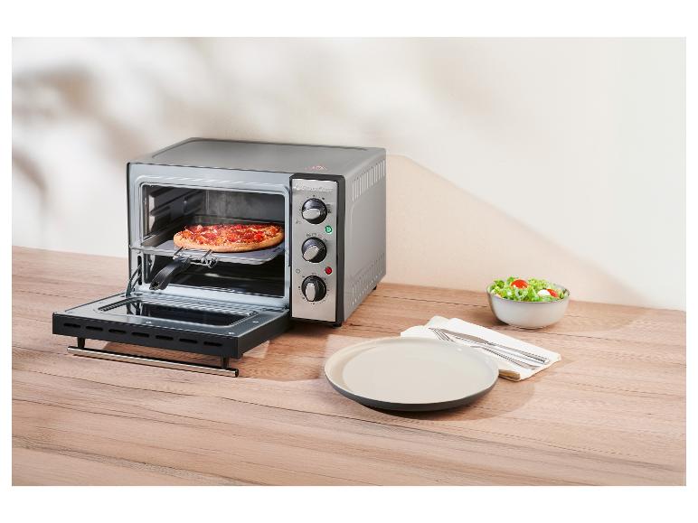 Mini-four SilverCrest avec une pizza à l'intérieur, à côté d'une assiette et d'un saladier.