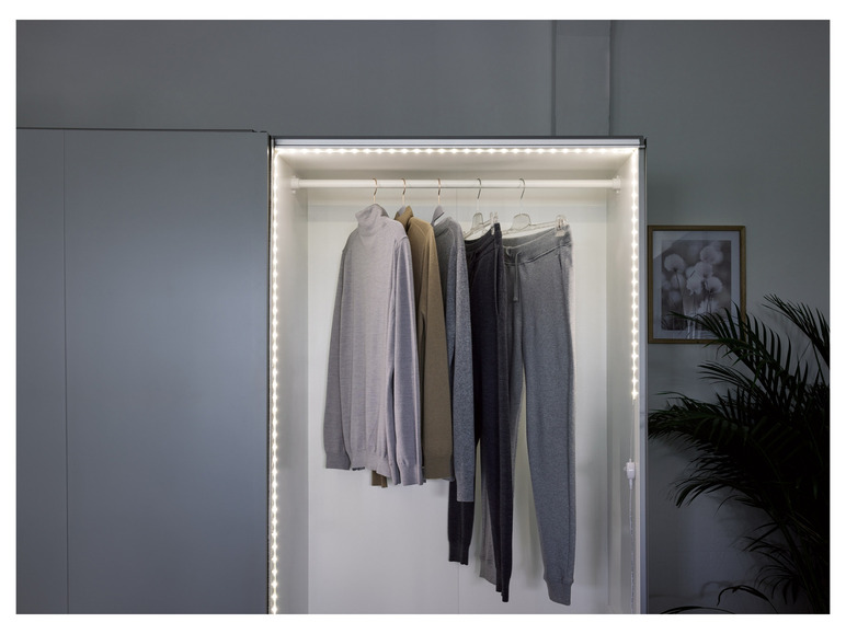 Éclairage LED à l'intérieur d'un placard avec des pulls et des pantalons
