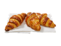 Trois croissants dorés aux cristaux de sucre sur une serviette blanche.