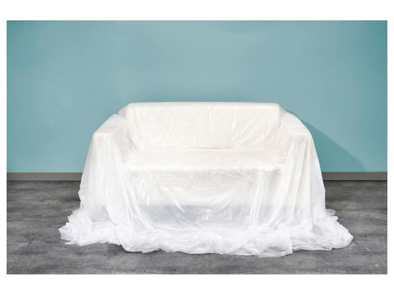 Canapé recouvert d'une bâche en plastique blanc devant un mur bleu clair