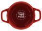 Cocotte rouge avec poignées et symboles de compatibilité de cuisson sur le dessous.