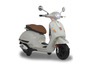 Un scooter Vespa blanc avec une selle en cuir marron.