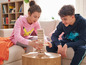 Deux adolescents jouent à Jenga sur un canapé.