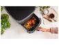 Une friteuse à air avec du poulet et des pommes de terre rôtis.