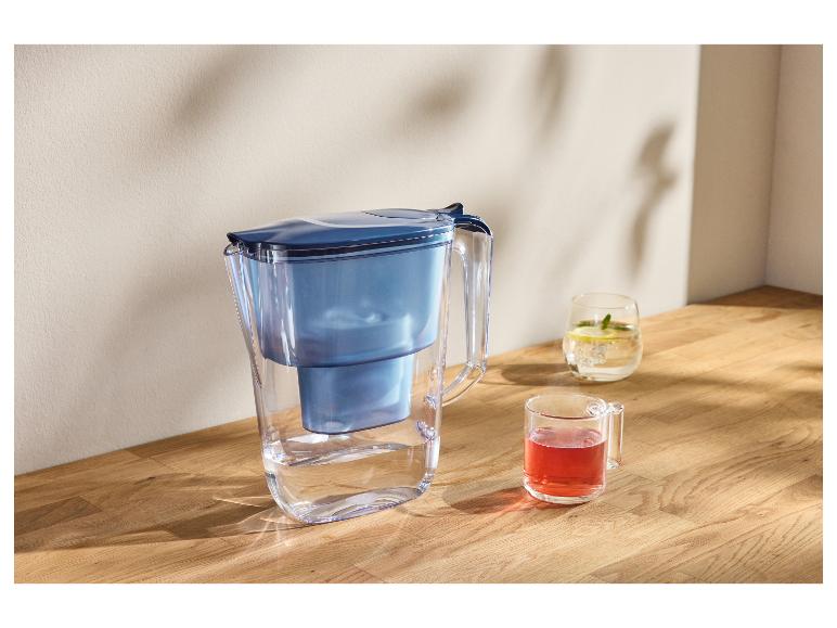 Carafe filtrante avec deux verres de boissons sur une surface en bois.