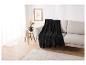 Une couverture en polaire noire sur un canapé beige avec un tapis blanc
