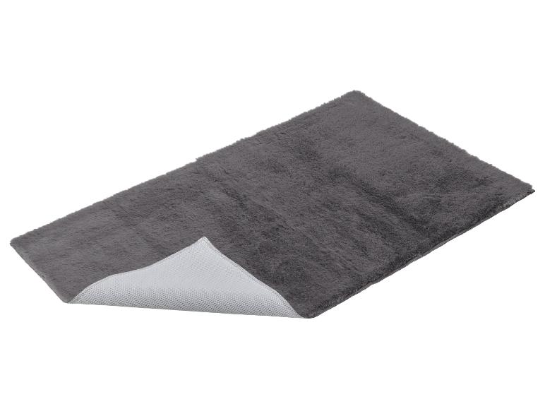Tapis de bain gris moelleux avec base antidérapante, vu en angle.