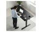 Homme travaillant sur un bureau réglable noir avec un ordinateur portable dans un bureau moderne.