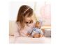 Fille en haut rose tenant une poupée bébé en pyjama à motifs et bonnet.