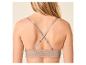 Femme de dos portant un soutien-gorge en dentelle beige à bretelles croisées.