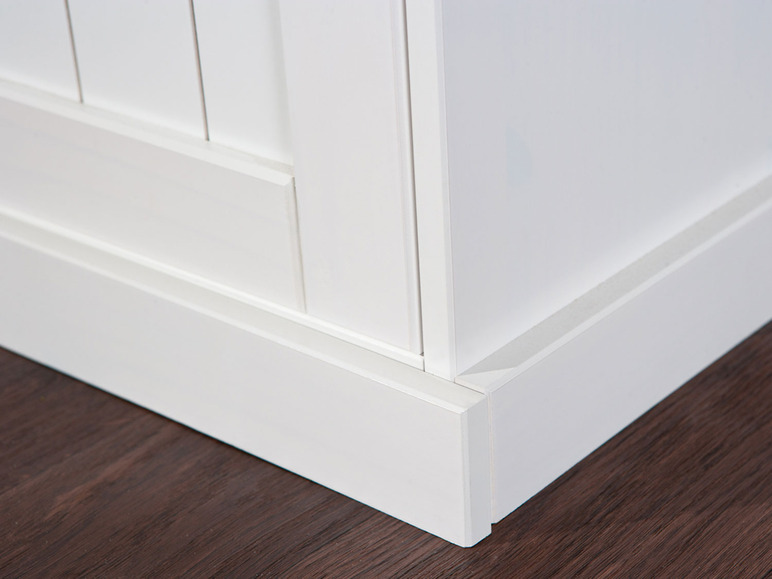 Plinthe blanche sur un sol en bois.