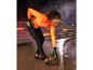 Femme en pull orange et leggings noirs s'étirant avant de courir.
