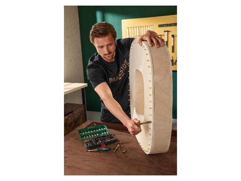 Homme assemblant une décoration murale en bois avec un set d'outils.