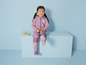 Une fille porte une combinaison rose avec un motif hibou et est assise sur un cube bleu.