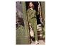 Une femme porte une chemise en satin vert, un pantalon et des baskets blanches.