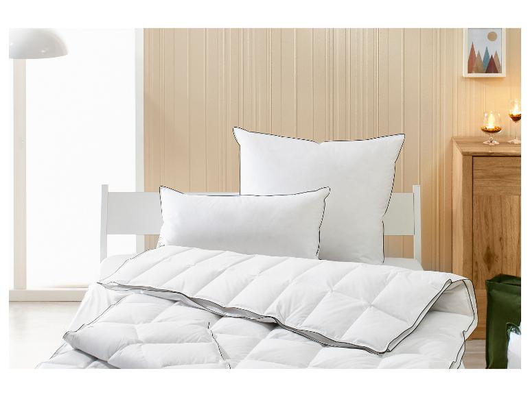 Couette et oreillers blancs avec passepoil noir dans une chambre lumineuse.