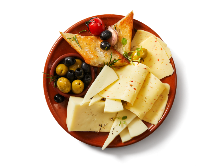 Assiette de fromages avec olives, pain grillé et tomates sur un plat de service marron.