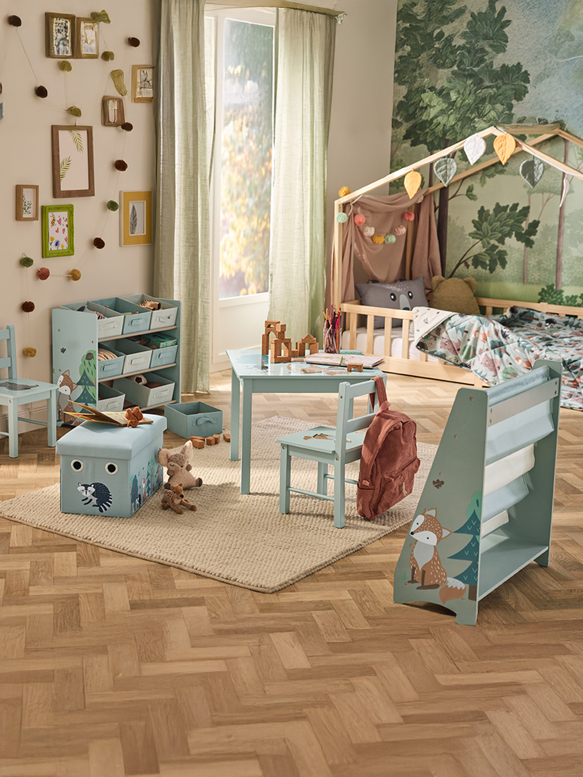 Une chambre d'enfant sur le thème de la forêt, avec un lit, une table, des chaises et des rangements.