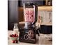 Mixeur préparant un smoothie aux baies sur un comptoir de cuisine, avec baies et lait.