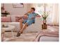 Homme en polo et short bleu clair assis sur un canapé beige dans un salon.