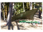 Une tente tarp verte et un sac de couchage dans une forêt.