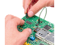 Mains connectant des fils à une carte de circuit imprimé verte avec des composants électroniques.