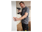 Un homme utilise une perceuse Parkside pour fixer une plaque blanche à un mur.